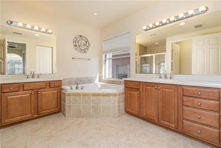 Bathroom with two vanities, shower with separate oversized bathtub, and tile patterned flooring.