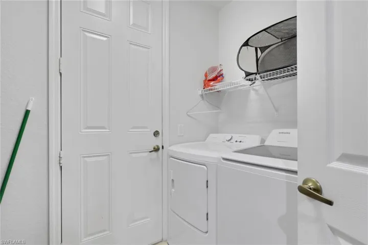 Dedicated laundry area featuring a white paneled door, wire shelving, and overhead storage