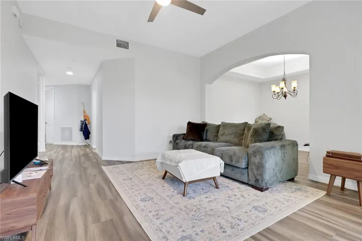Expansive living area featuring light wood-finish flooring, a contemporary ceiling fan, and crisp white walls