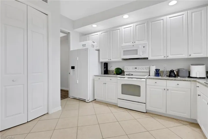 Kitchen featuring white cabinetry, light-toned granite countertops, and recessed lighting