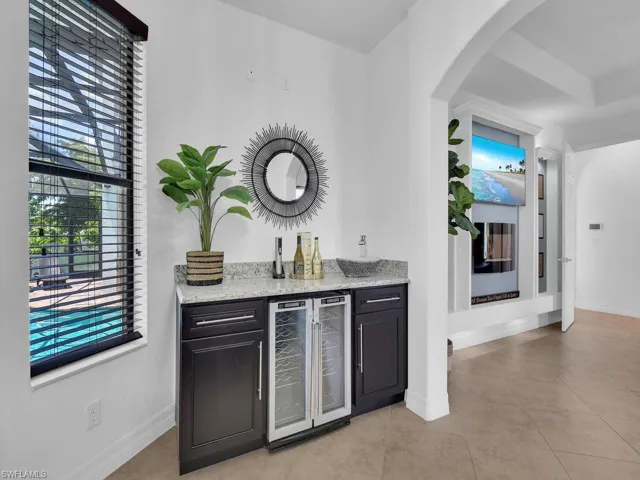 Bar featuring light stone counters, light tile patterned flooring, and beverage cooler