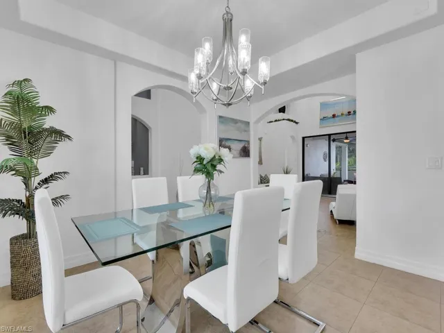 Dining area with light tile patterned floors, an inviting chandelier, and a raised ceiling