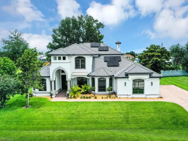 View of front of home featuring solar panels and a front yard
