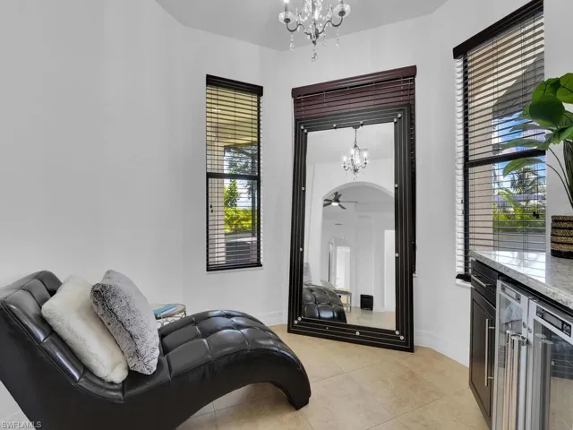 Sitting room featuring light tile patterned floors, ceiling fan with notable chandelier, and beverage cooler