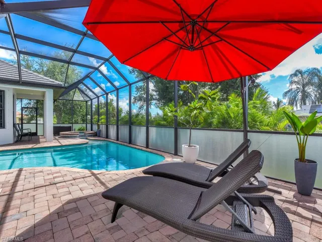 View of pool featuring an in ground hot tub, glass enclosure, and a patio area