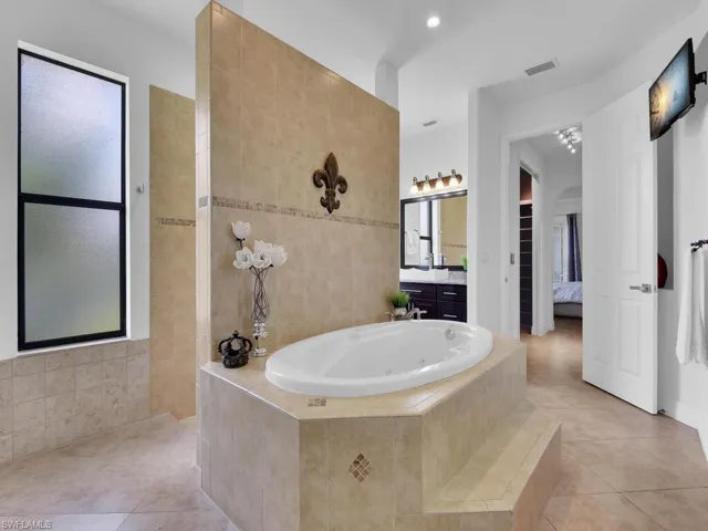 Bathroom featuring tile patterned flooring, vanity, and shower with separate bathtub