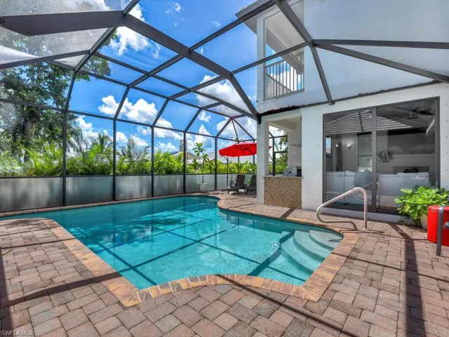 View of swimming pool with glass enclosure and a patio