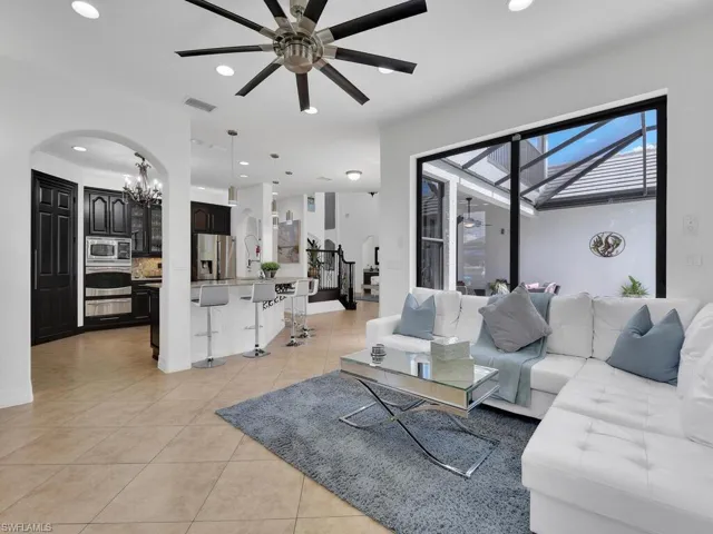 Living room with light tile patterned floors and ceiling fan with notable chandelier