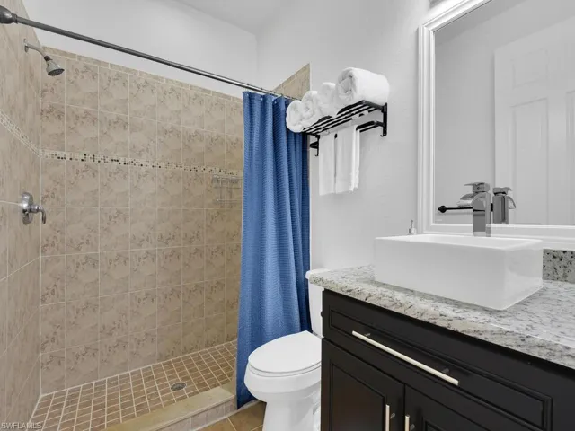 Bathroom featuring tile patterned flooring, vanity, a shower with shower curtain, and toilet