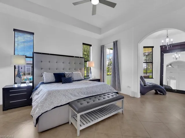 Bedroom with ceiling fan with notable chandelier and light tile patterned floors