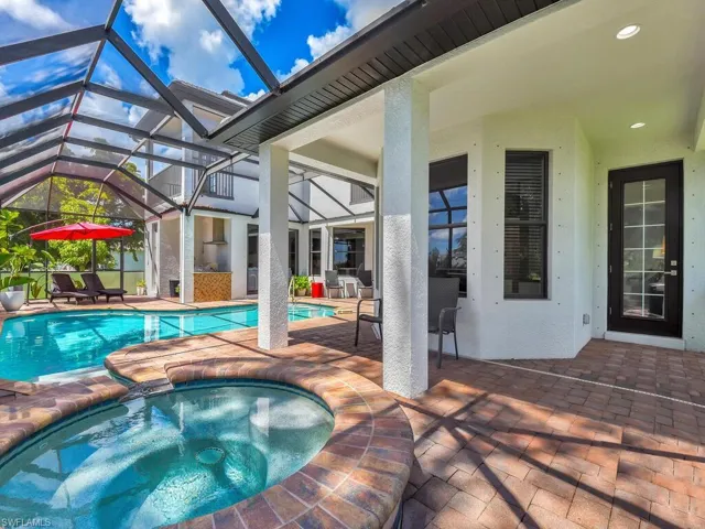 View of swimming pool with a patio area, an in ground hot tub, and glass enclosure