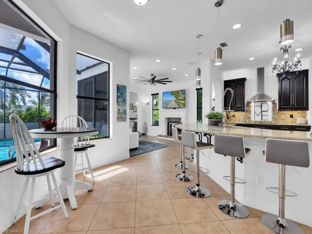 Kitchen featuring pendant lighting, a kitchen breakfast bar, wall chimney range hood, and tasteful backsplash
