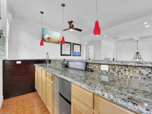 Kitchen with light brown cabinetry, decorative columns, ceiling fan, sink, and light tile patterned floors