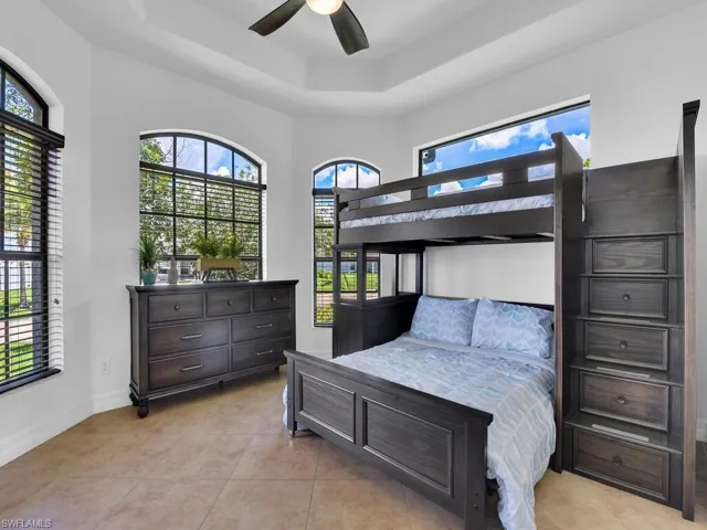 Tiled bedroom with a raised ceiling and ceiling fan
