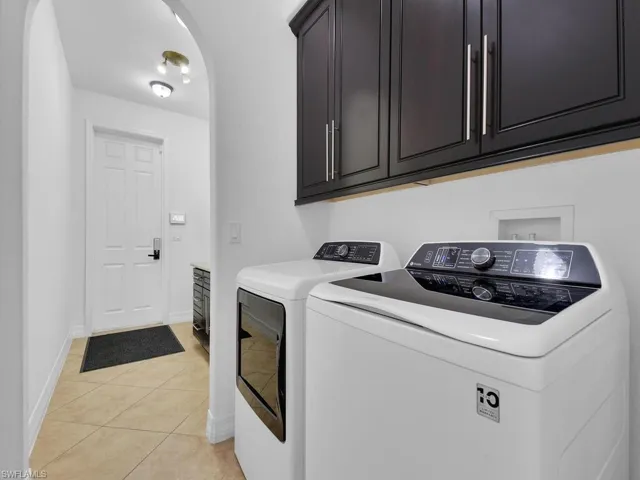 Laundry area with cabinets, independent washer and dryer, and light tile patterned flooring
