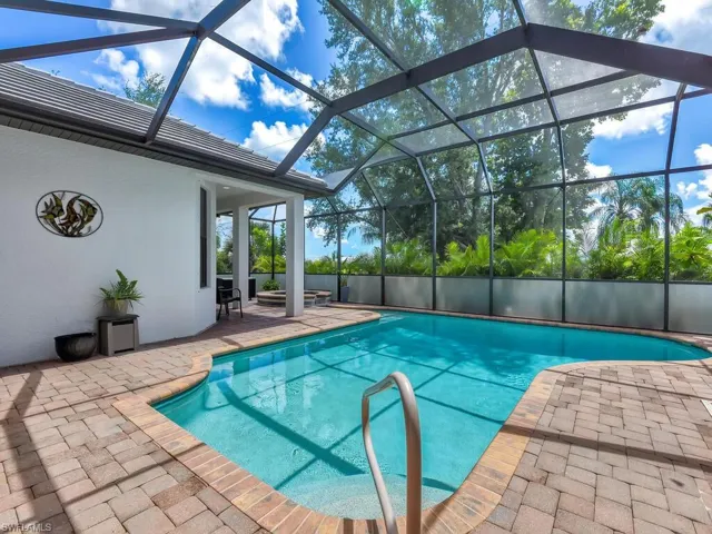 View of swimming pool with glass enclosure and a patio area