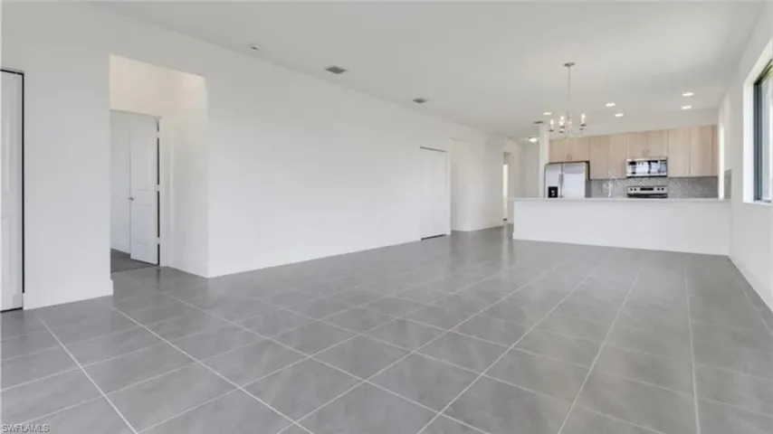 Unfurnished living room with dark tile patterned floors, recessed lighting, and a chandelier