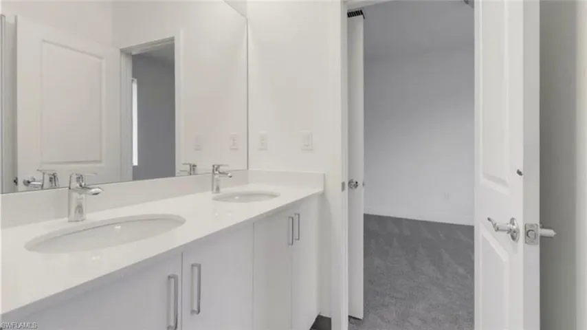Full bathroom with double vanity and baseboards