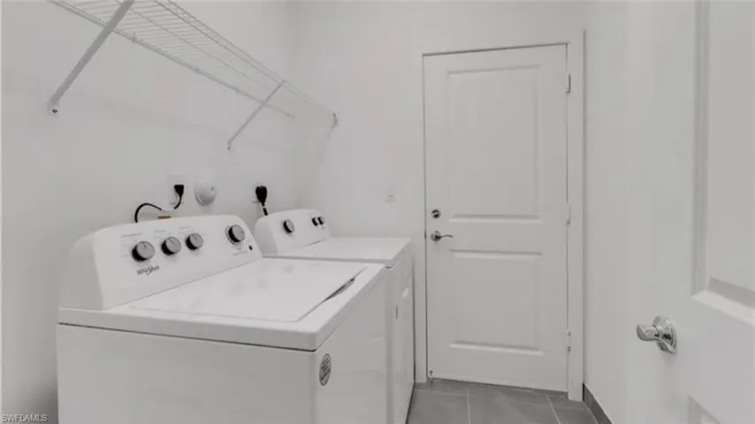 Washroom with tile patterned flooring and washer and dryer