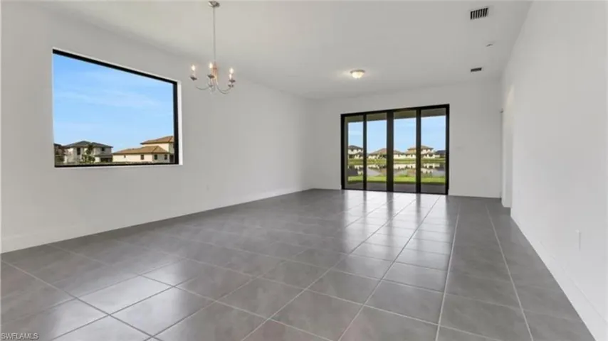Unfurnished room with dark tile patterned floors and a chandelier