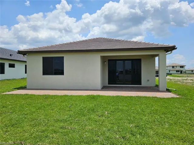 Back of house with a patio area, a yard, stucco siding, and a tile roof