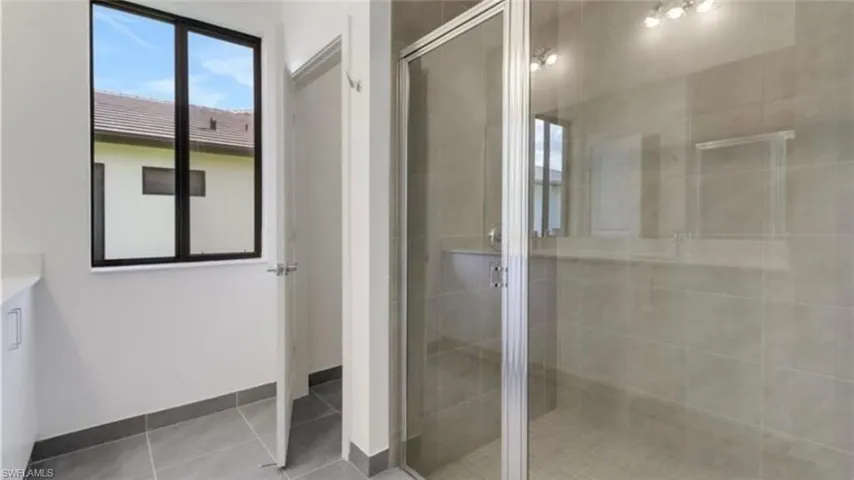 Full bathroom featuring vanity, a stall shower, and light tile patterned flooring