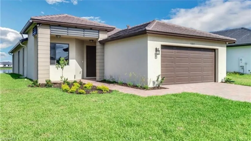 View of front of property featuring stucco siding, a front yard, a garage, and decorative driveway