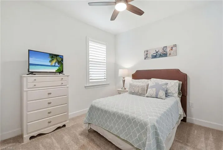 Carpeted room featuring a ceiling fan with integrated lighting, a window with white louvered shutters, and light-toned walls