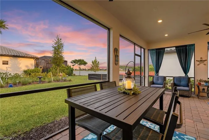 Screened outdoor living area featuring brick paver flooring and a ceiling fan