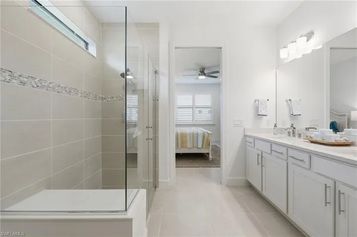Bathroom featuring a spacious walk-in shower with clear glass enclosure and light-toned tilework with mosaic accent band