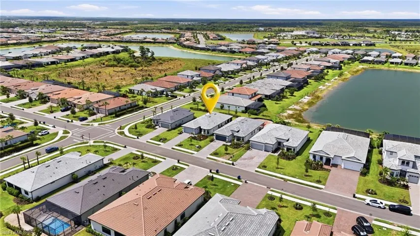 Aerial perspective of a developed residential community featuring numerous single-story homes with individual driveways and manicured lawns