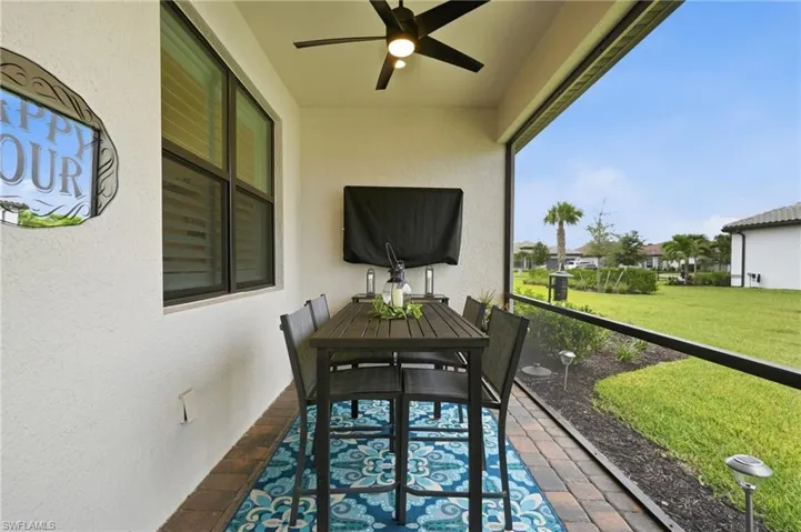 Screened outdoor patio featuring a ceiling fan, a mounted fixture, and brick-patterned flooring