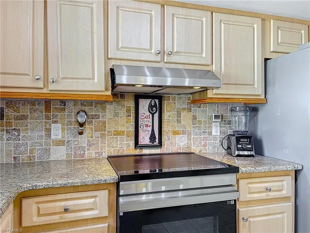 Kitchen featuring tile patterned flooring, appliances with stainless steel finishes, decorative backsplash, and light brown cabinetry