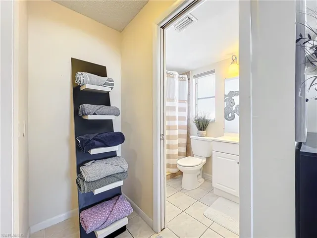 Bathroom with toilet, tile patterned flooring, a textured ceiling, vanity, and walk in shower