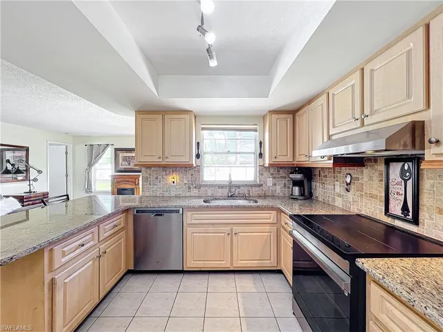 Kitchen with light tile patterned floors, a wealth of natural light, sink, and appliances with stainless steel finishes