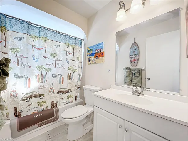 Full bathroom featuring shower / bath combo, tile patterned flooring, vanity, and toilet
