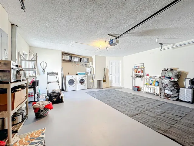 Garage with a garage door opener, water heater, and washing machine and clothes dryer
