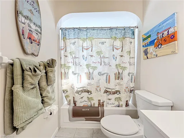 Full bathroom with toilet, shower / tub combo with curtain, vanity, and tile patterned floors