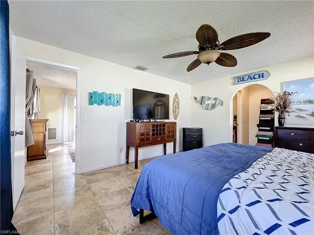 Bedroom with ceiling fan and a textured ceiling