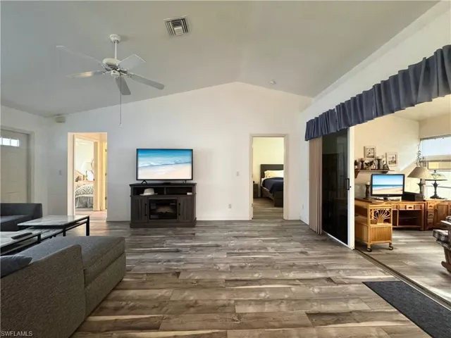 Living area featuring vaulted ceiling, wood finished floors, and ceiling fan
