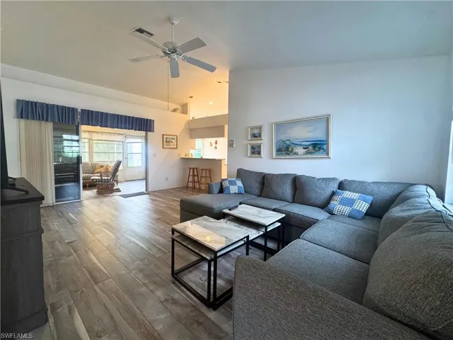 Living area with wood finished floors, high vaulted ceiling, and a ceiling fan