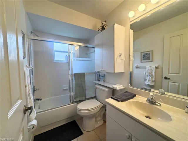Bathroom featuring vanity, light tile patterned floors, and combined bath / shower with glass door