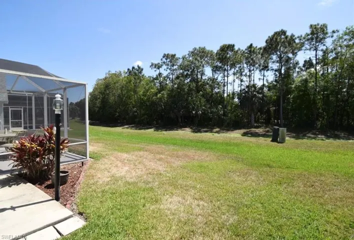 View of grassy yard featuring a lanai and a sunroom