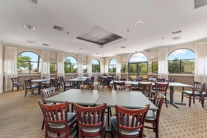 Dining room with light colored carpet, plenty of natural light, a raised ceiling, and ornamental molding