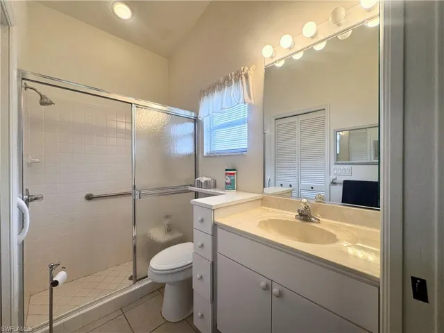 Full bath with vanity, light tile patterned floors, and a shower stall
