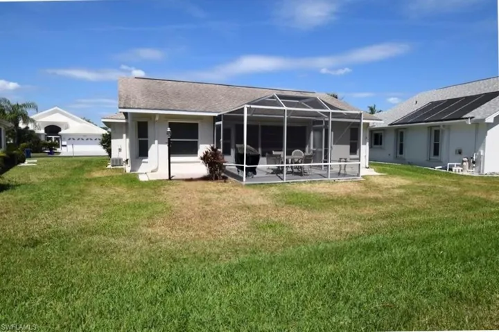 Back of house with a sunroom, a lanai, a yard, and a shingled roof
