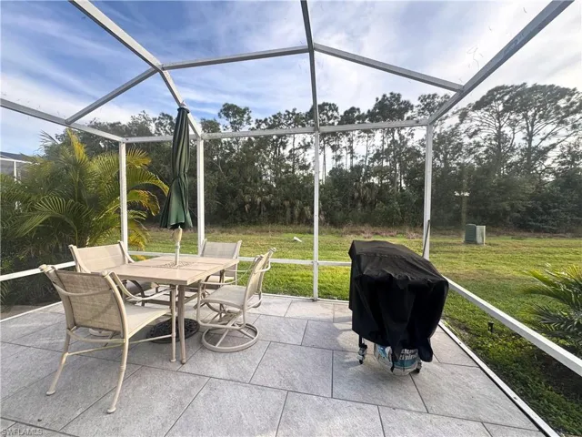 View of patio featuring a sunroom, glass enclosure, outdoor dining area, and a grill