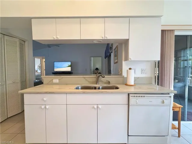 Kitchen with light tile patterned floors, white cabinets, and dishwasher