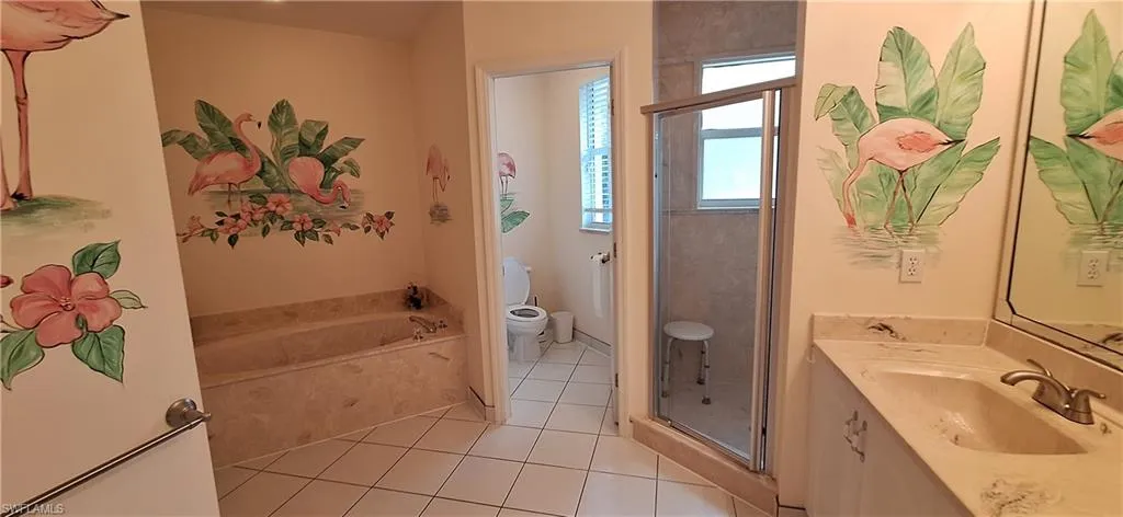 Full bath featuring toilet, tile patterned flooring, vanity, a stall shower, and a garden tub