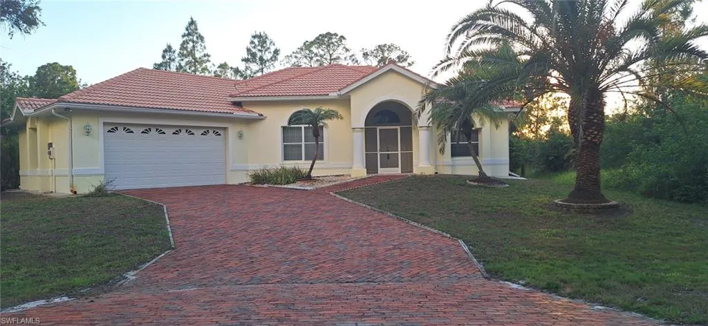 Mediterranean / spanish-style home featuring decorative driveway, a garage, a front yard, and a tile roof